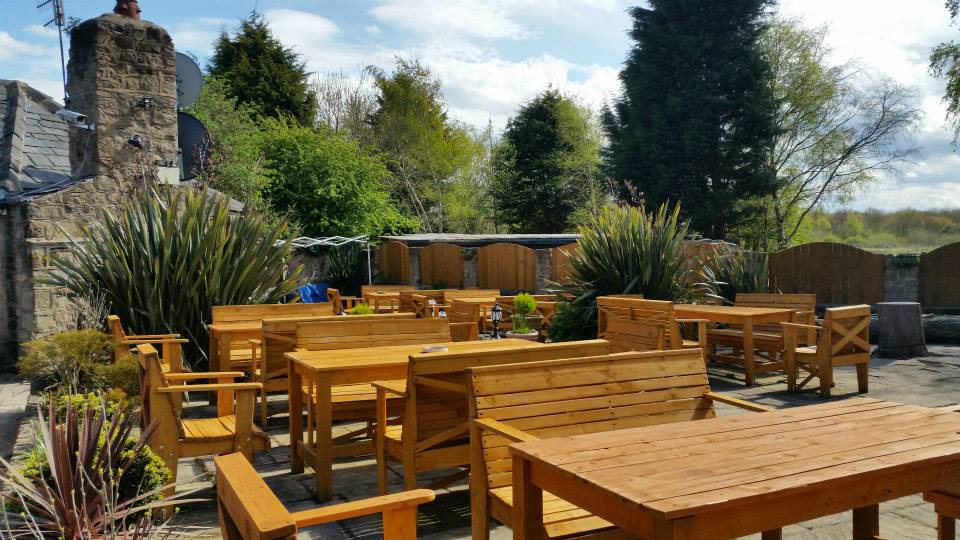 Outdoor patio with wooden tables and chairs.