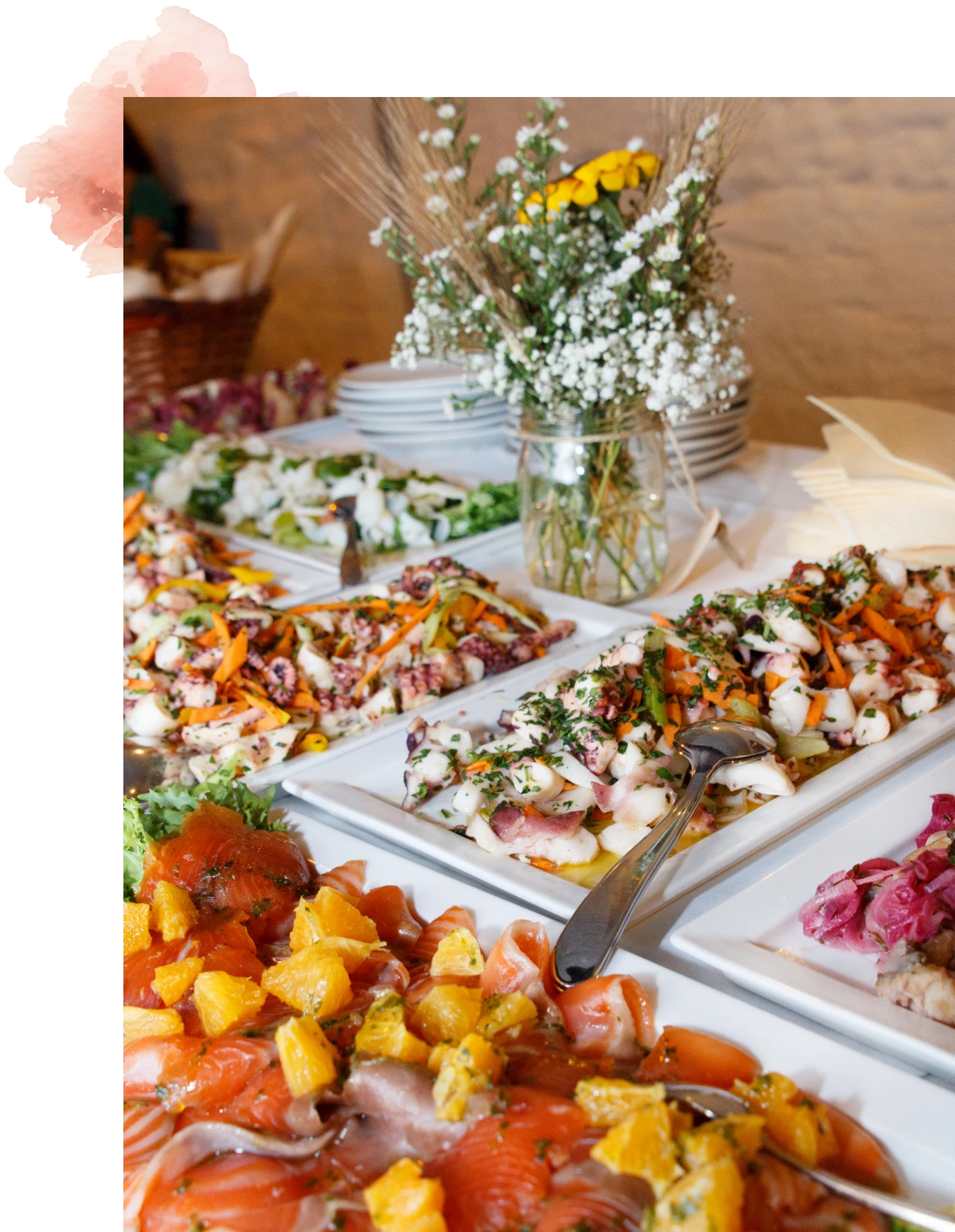 Buffet with assorted platters and floral arrangement.