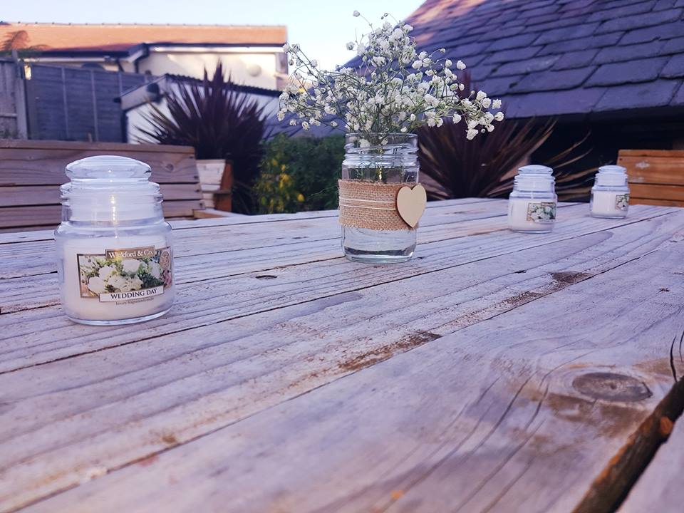Candles and flowers on rustic wooden table.
