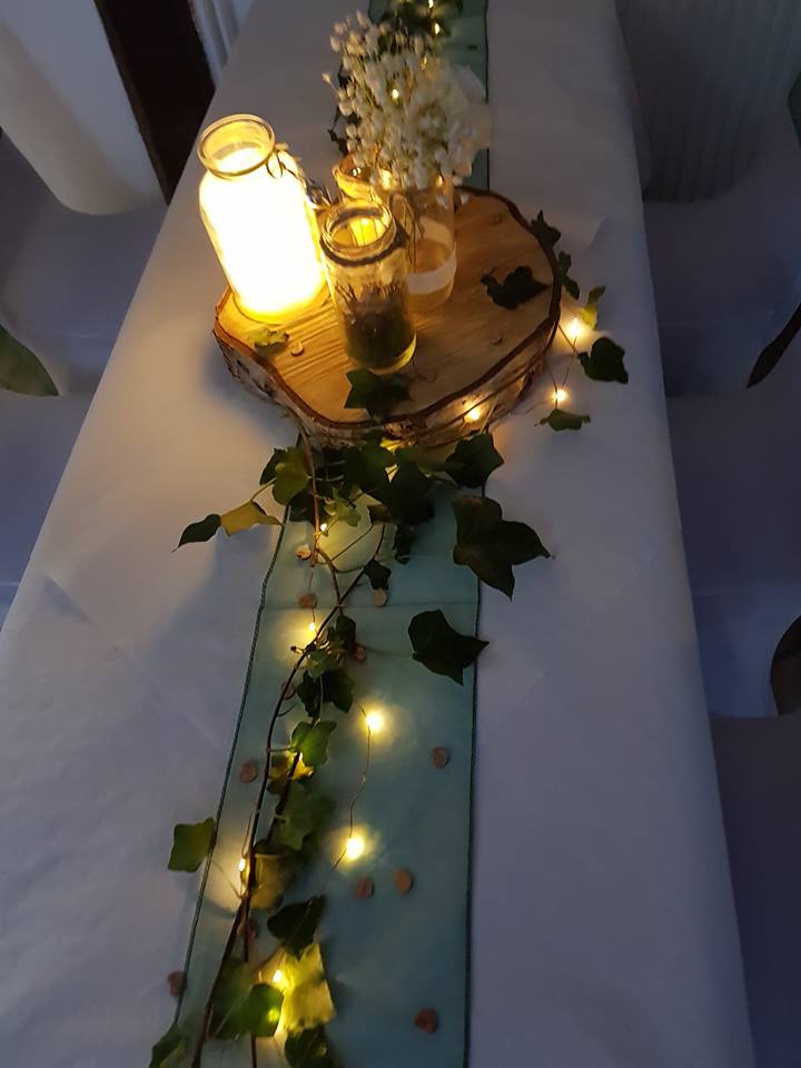 Table centerpiece with candles and greenery.