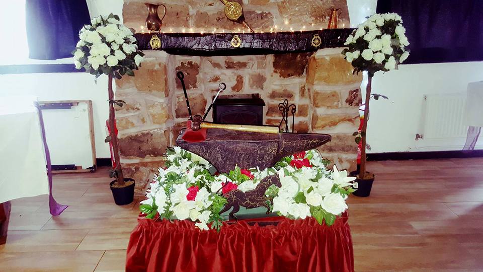 Sword in stone with floral arrangement display.